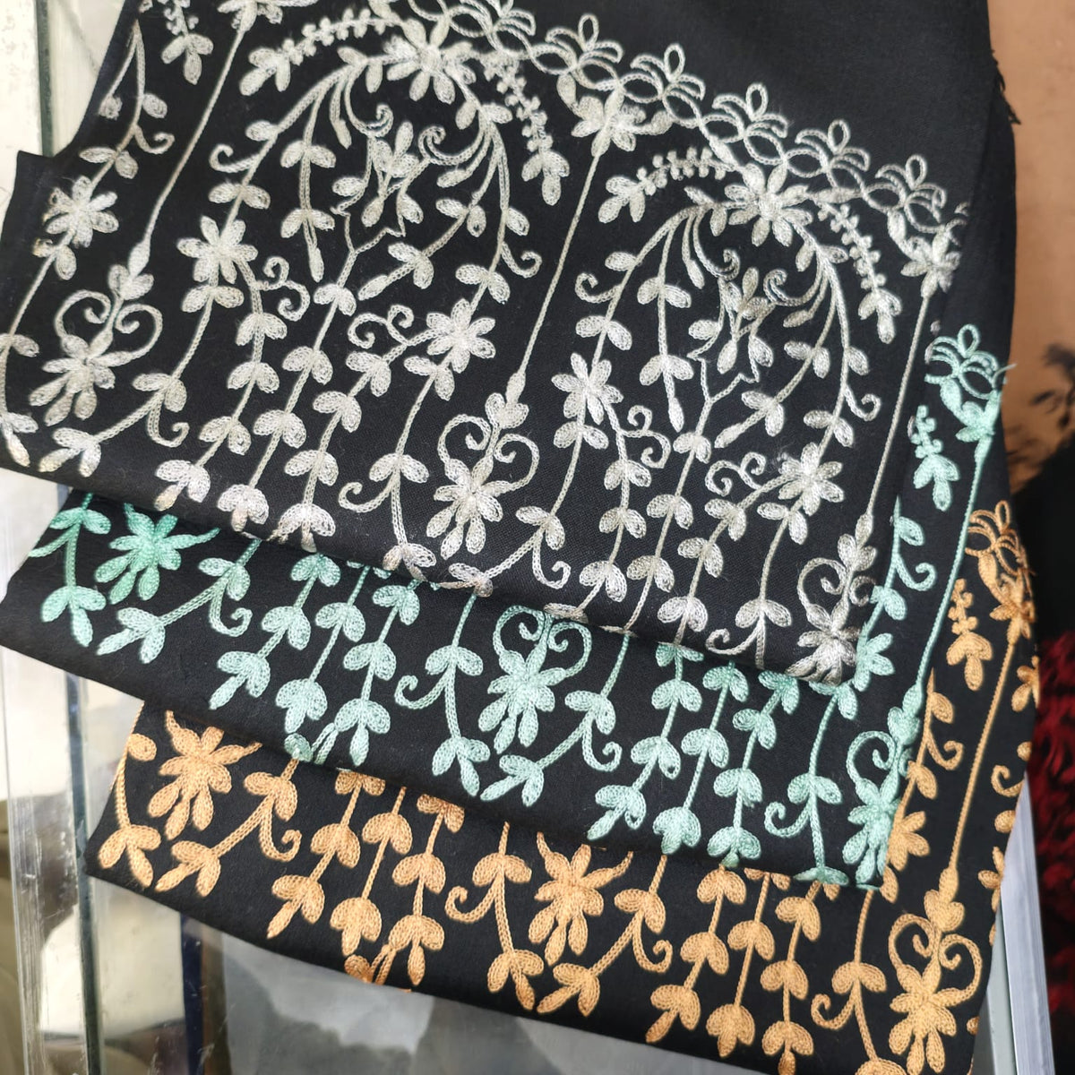 Women's black floral-vine embroidered shawls photographed in several thread colors